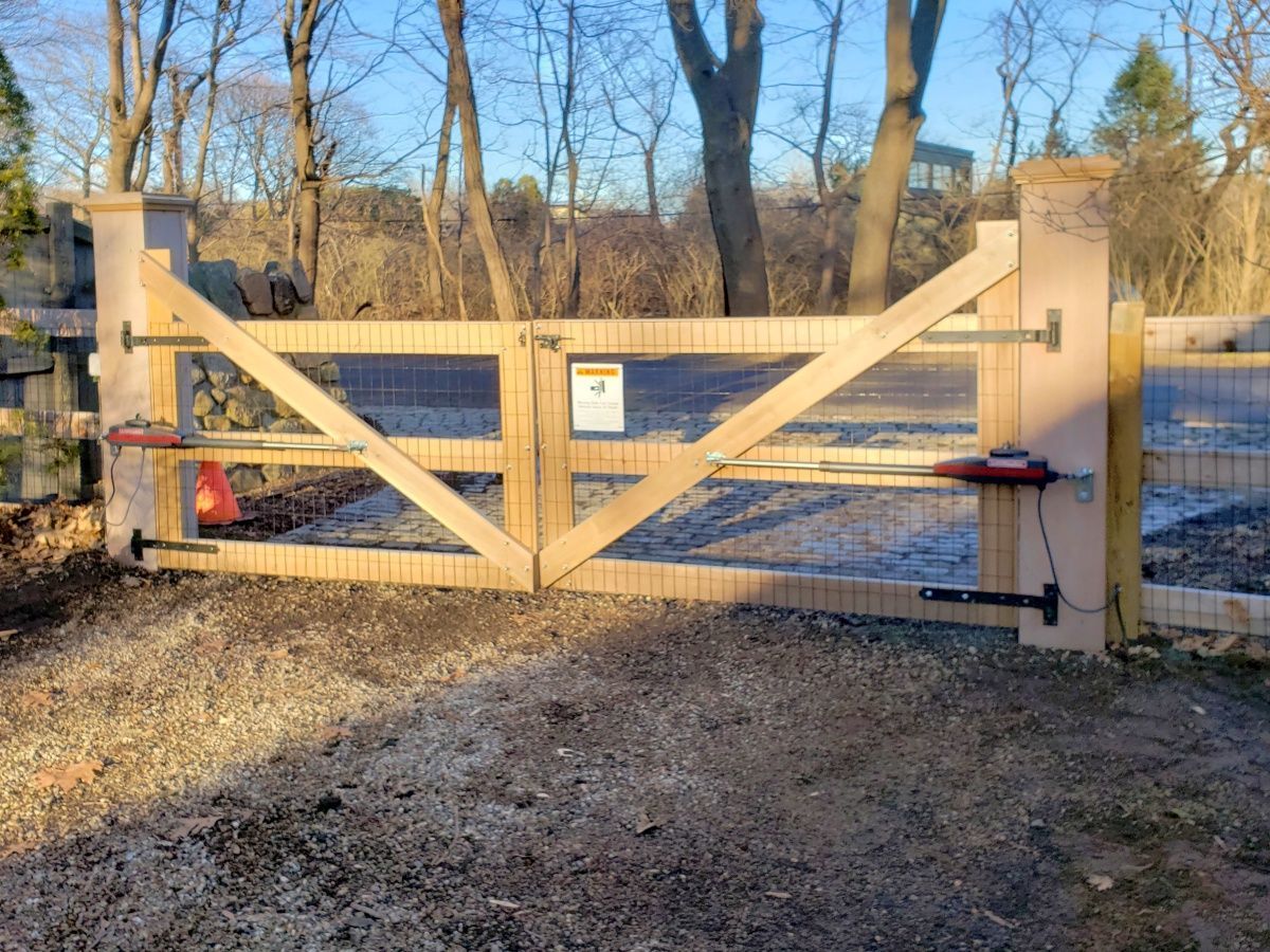 A wooden gate with a motor attached to it is surrounded by trees.