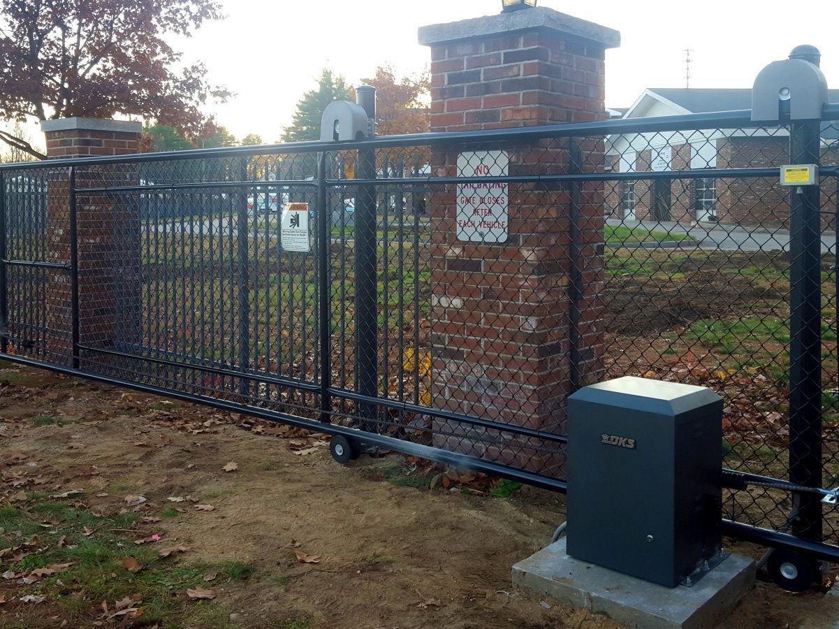 A black sliding gate with a black box in front of it.