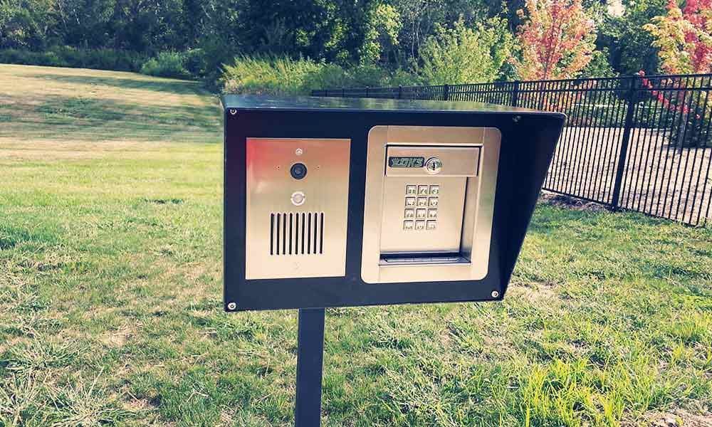 A telephone booth is sitting in the grass next to a fence.