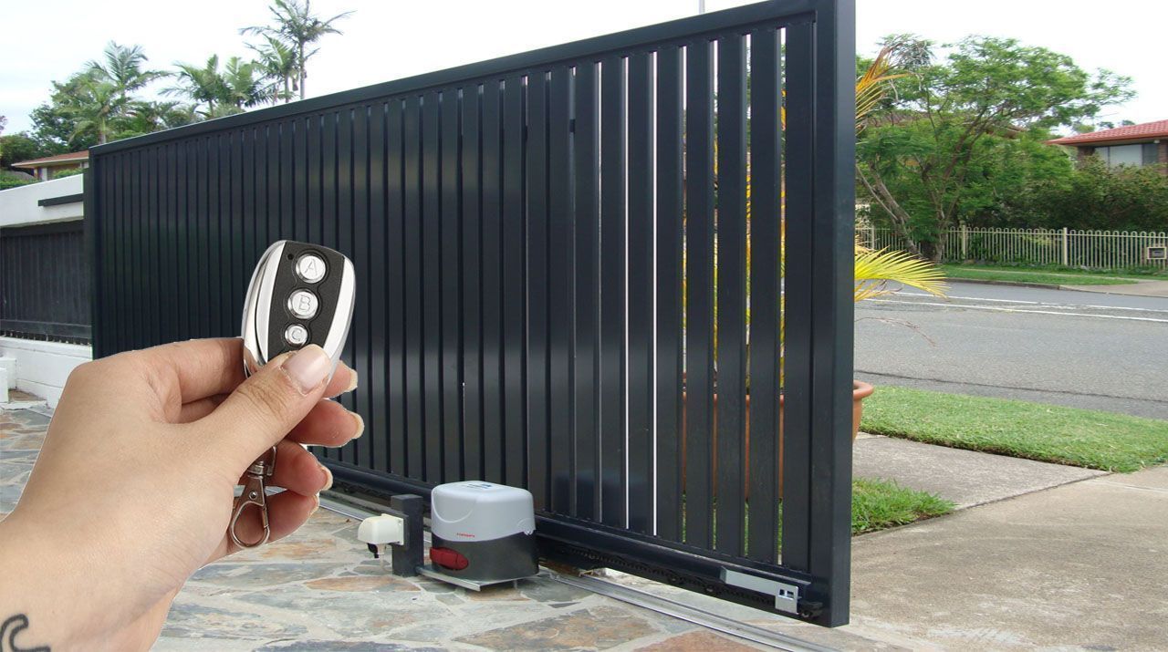 A person is holding a remote control in front of a sliding gate.