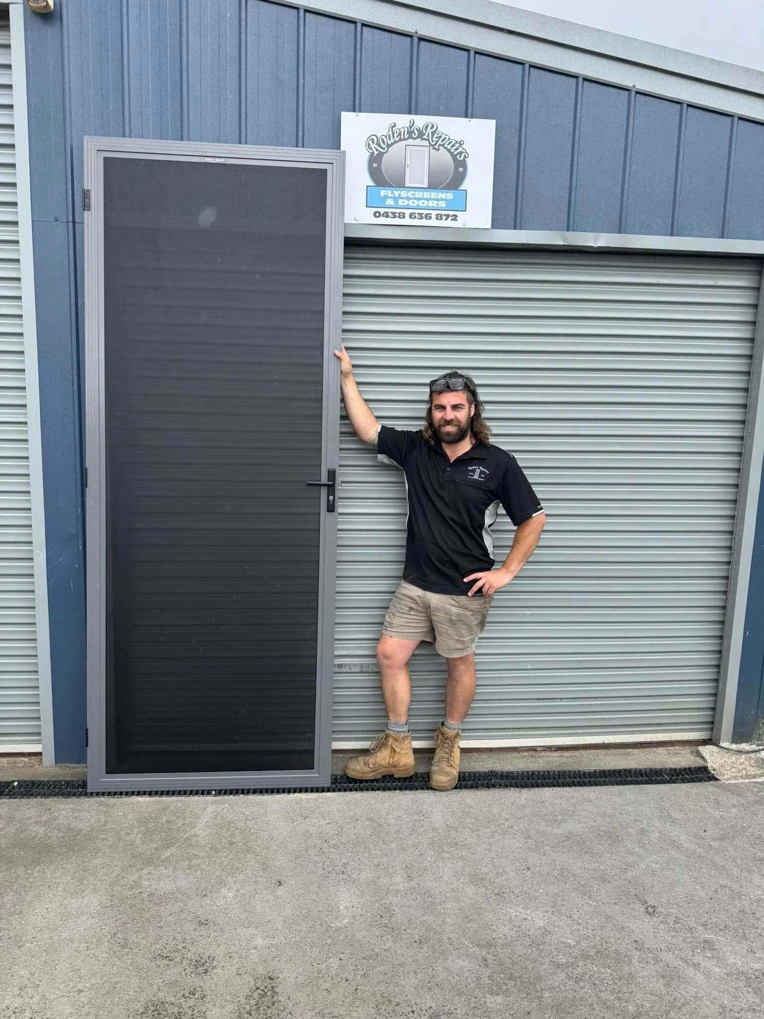 A Person Stands Next to a Gray Security Screen Door — Rodens Repairs Flyscreens and Doors In Forcett, TAS