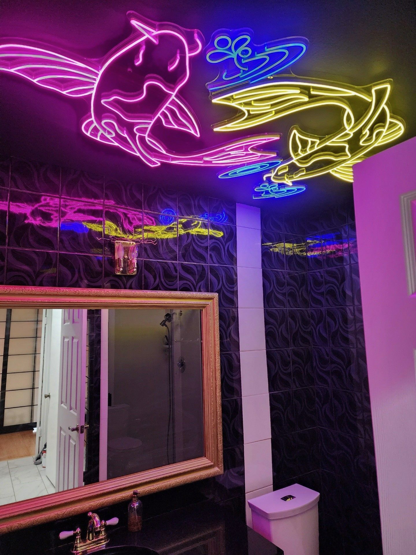 A bathroom with a neon sign on the ceiling and a mirror.