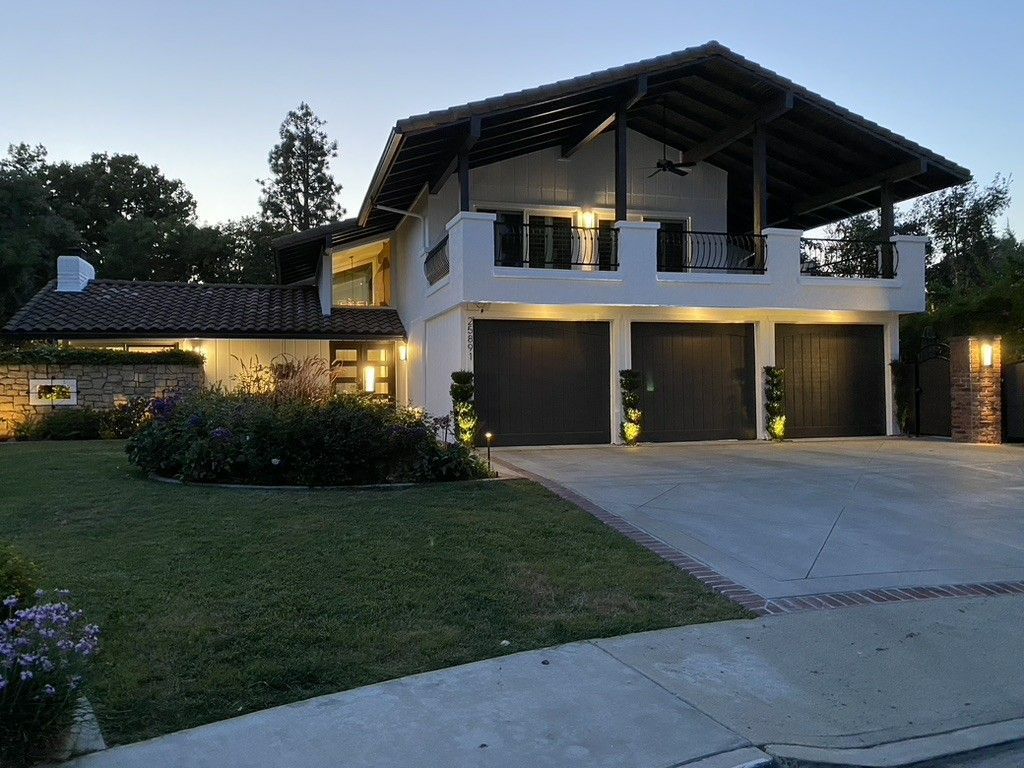A large house with three garage doors is lit up at night
