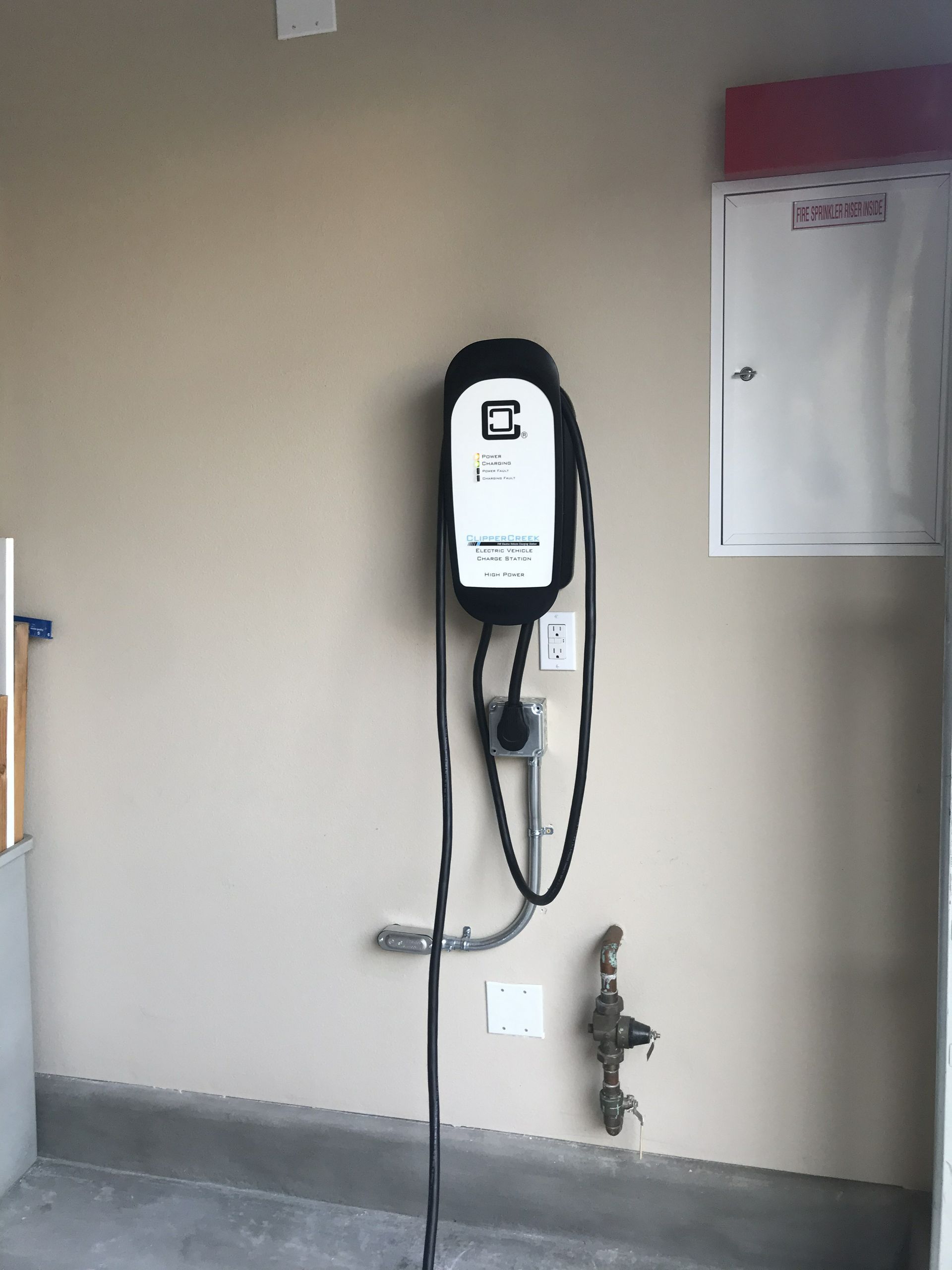 An electric car charger is hanging on a wall in a garage.