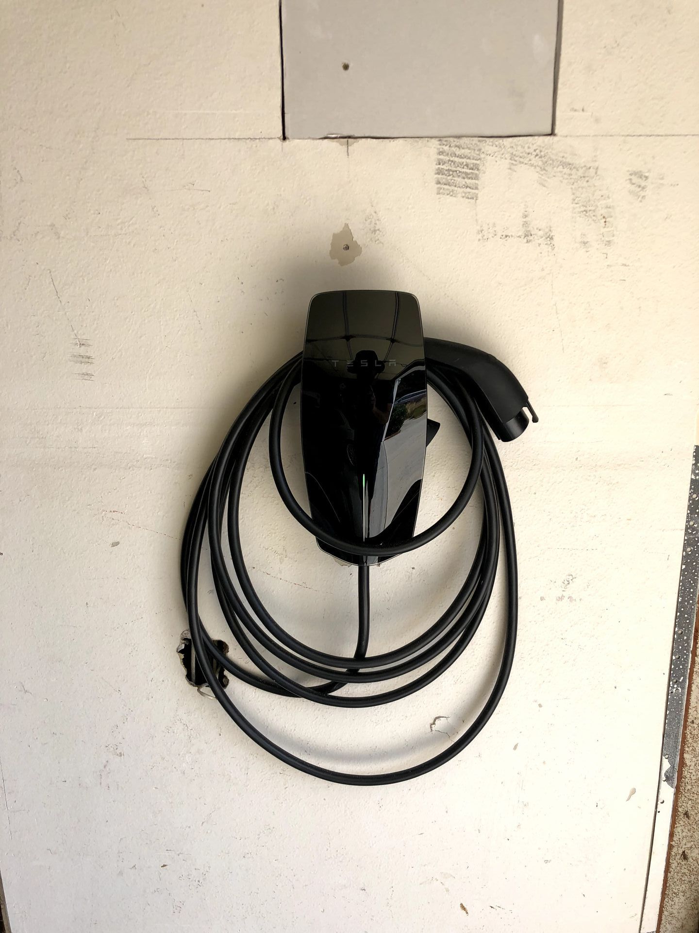 A black cord is hanging on a white wall
