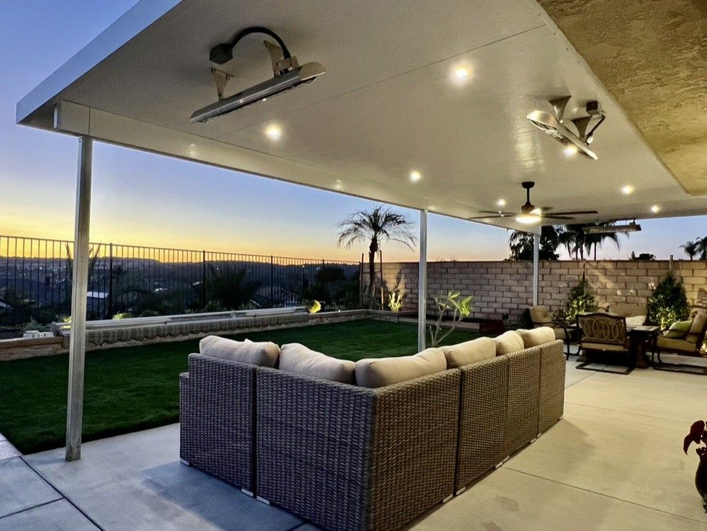 A patio with a large sectional couch and a ceiling fan