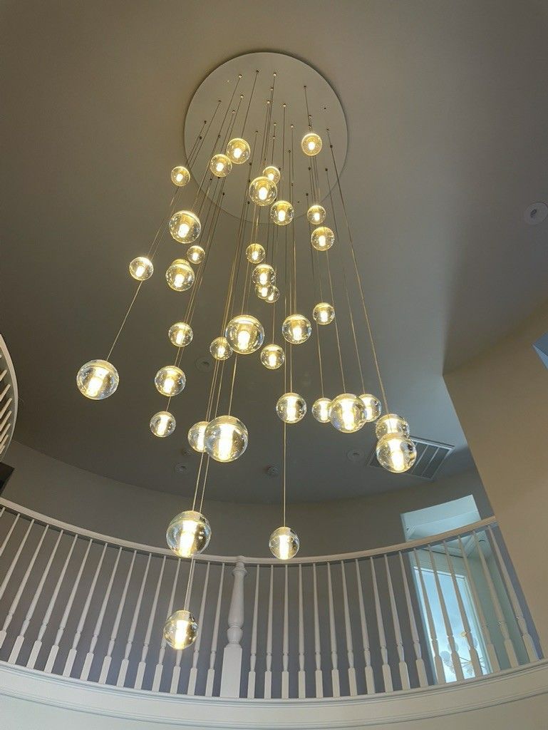 A large chandelier is hanging from the ceiling above a staircase.