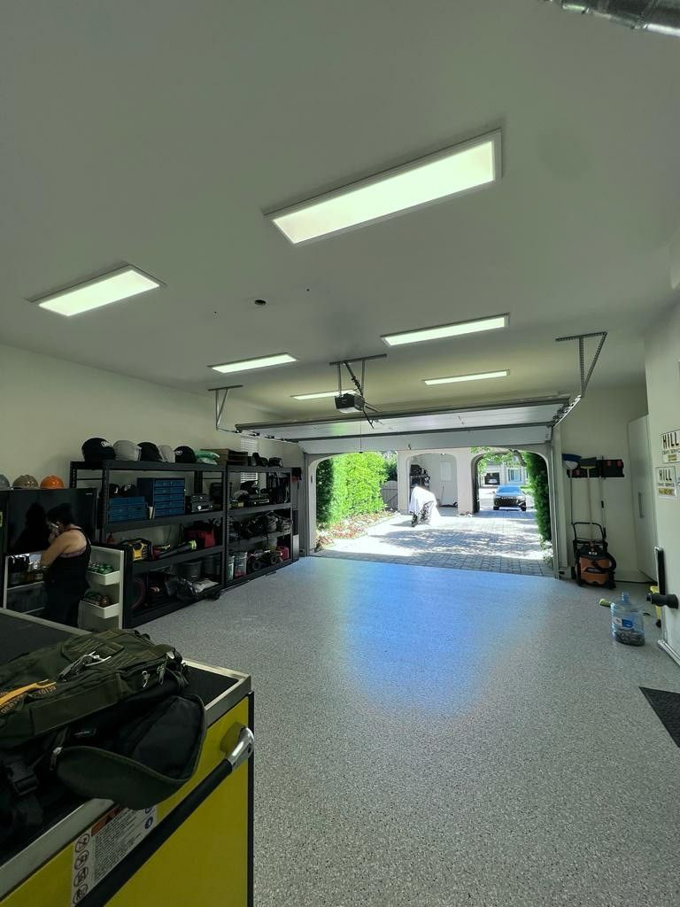 A large garage with a concrete floor and a garage door open.