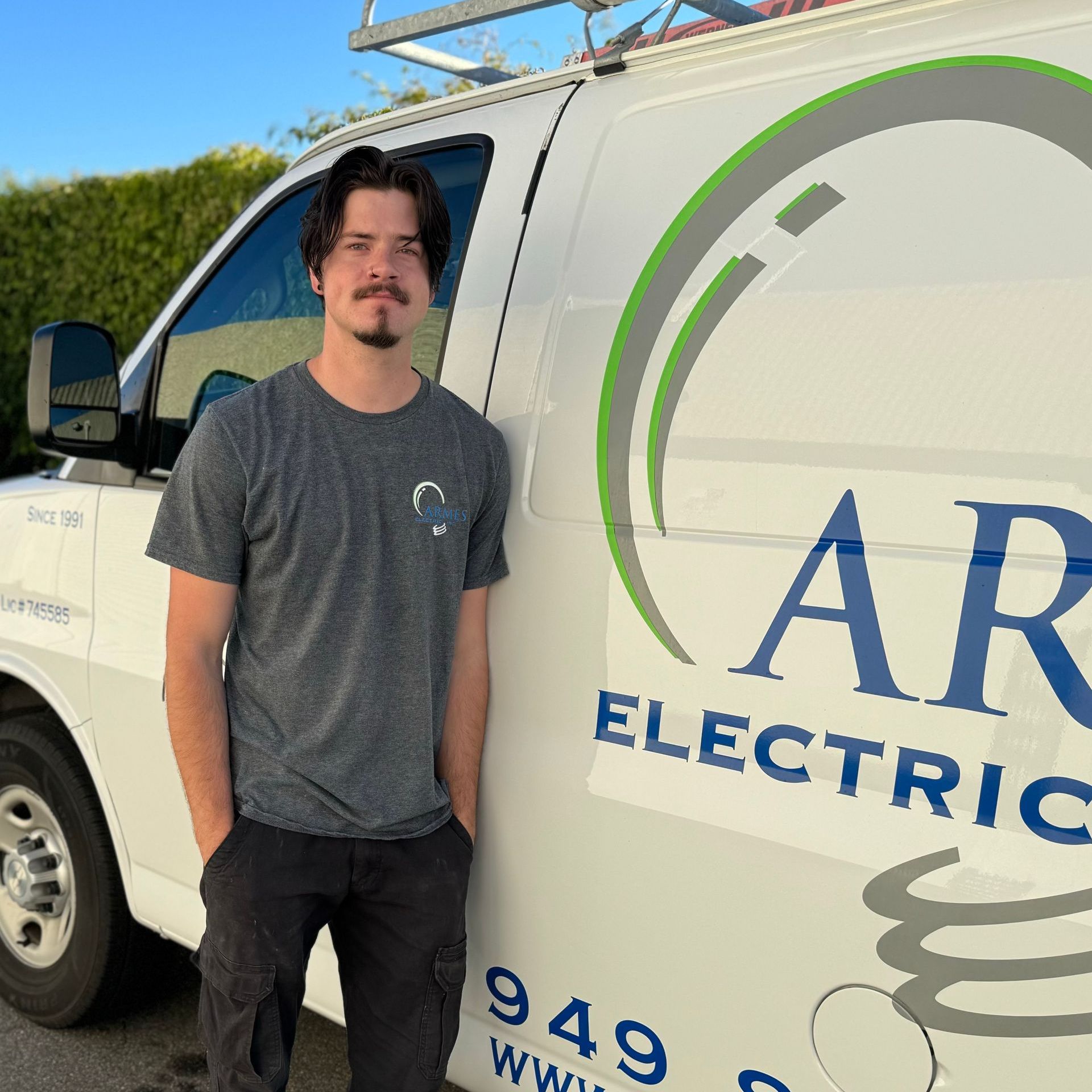 Person standing beside an AR Electric service van outdoors.