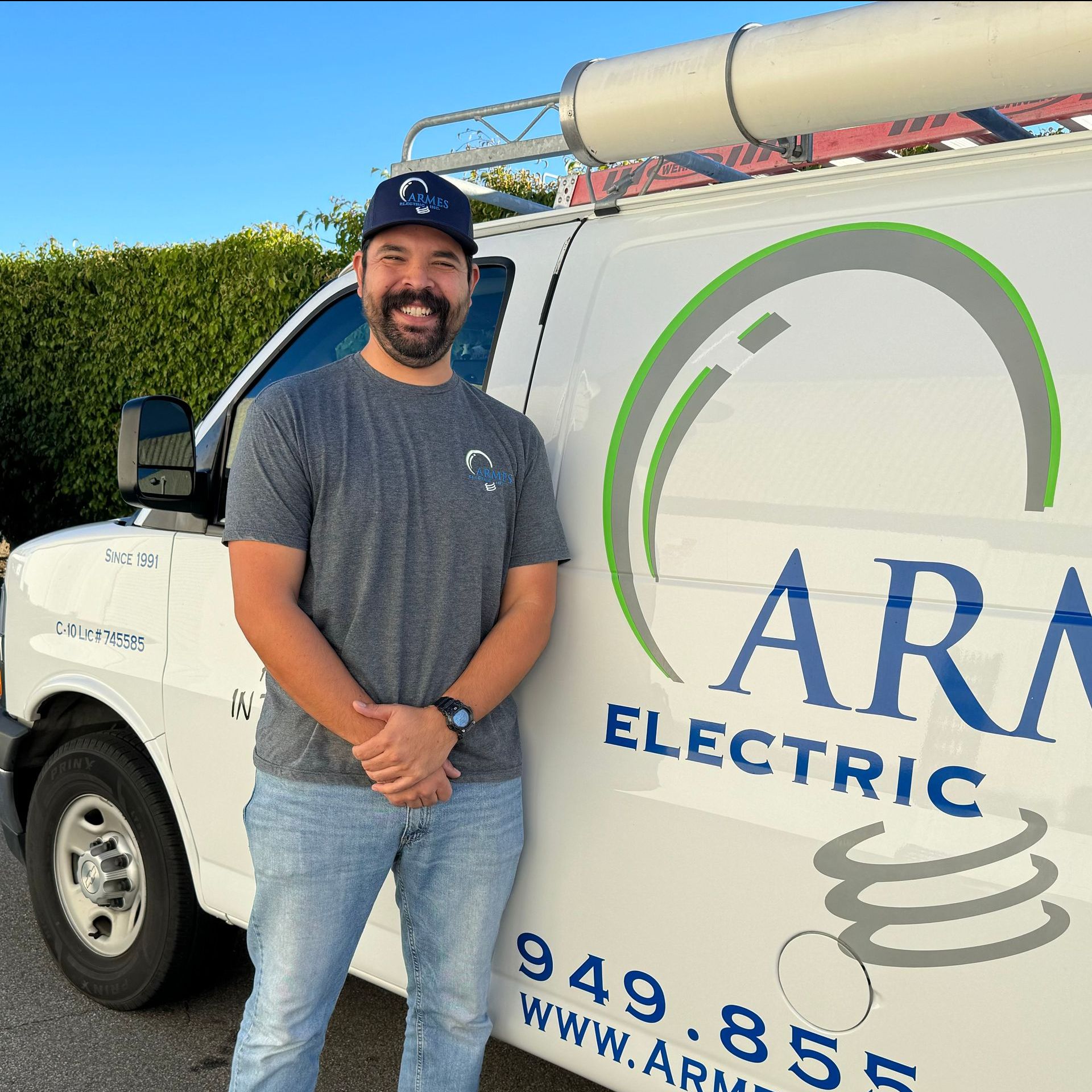 Man standing beside a white ARA Electric service van with company logo and ladder on top
