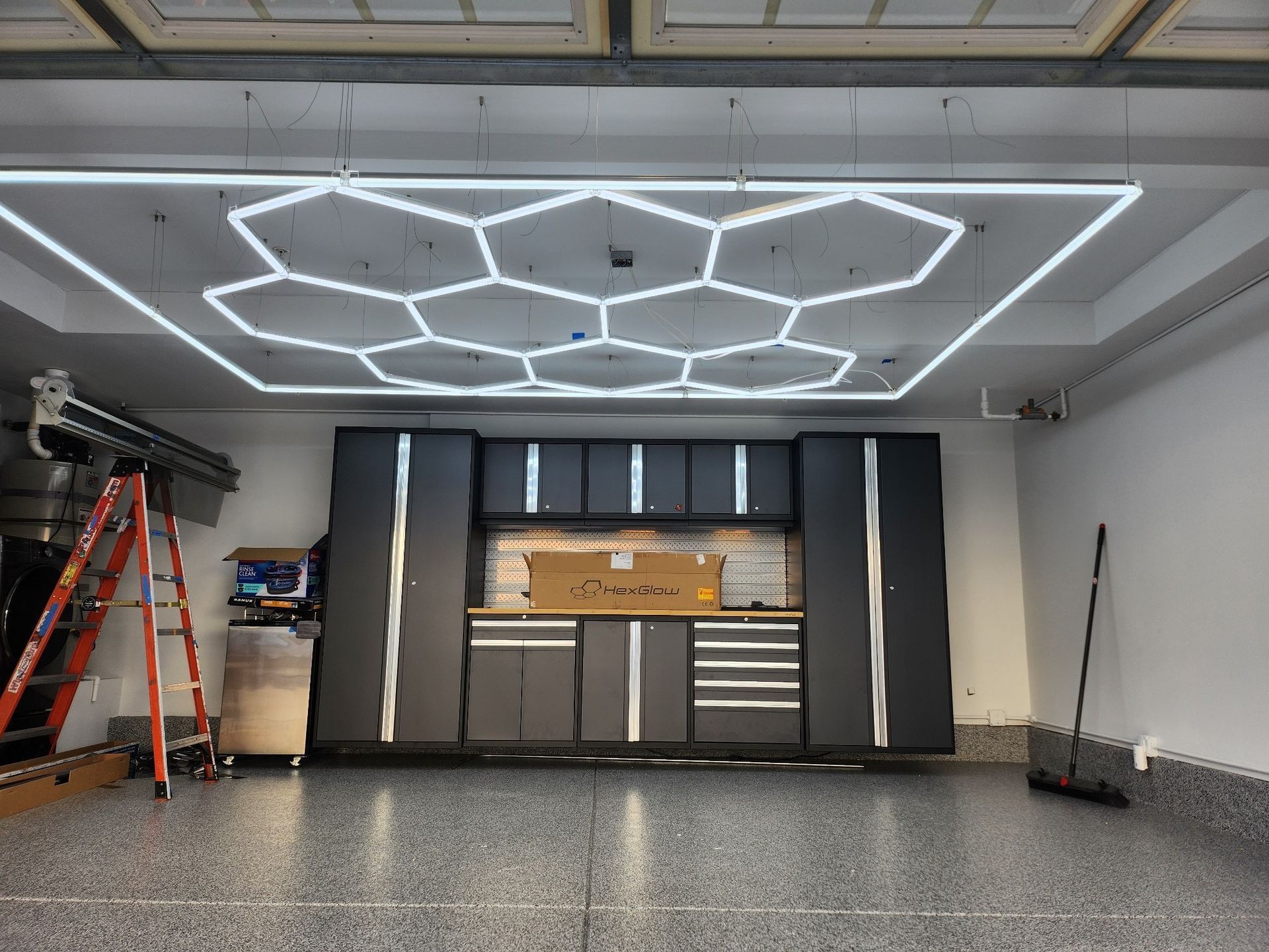 Garage with hexagon-shaped ceiling lights, dark gray cabinets, and a speckled floor.