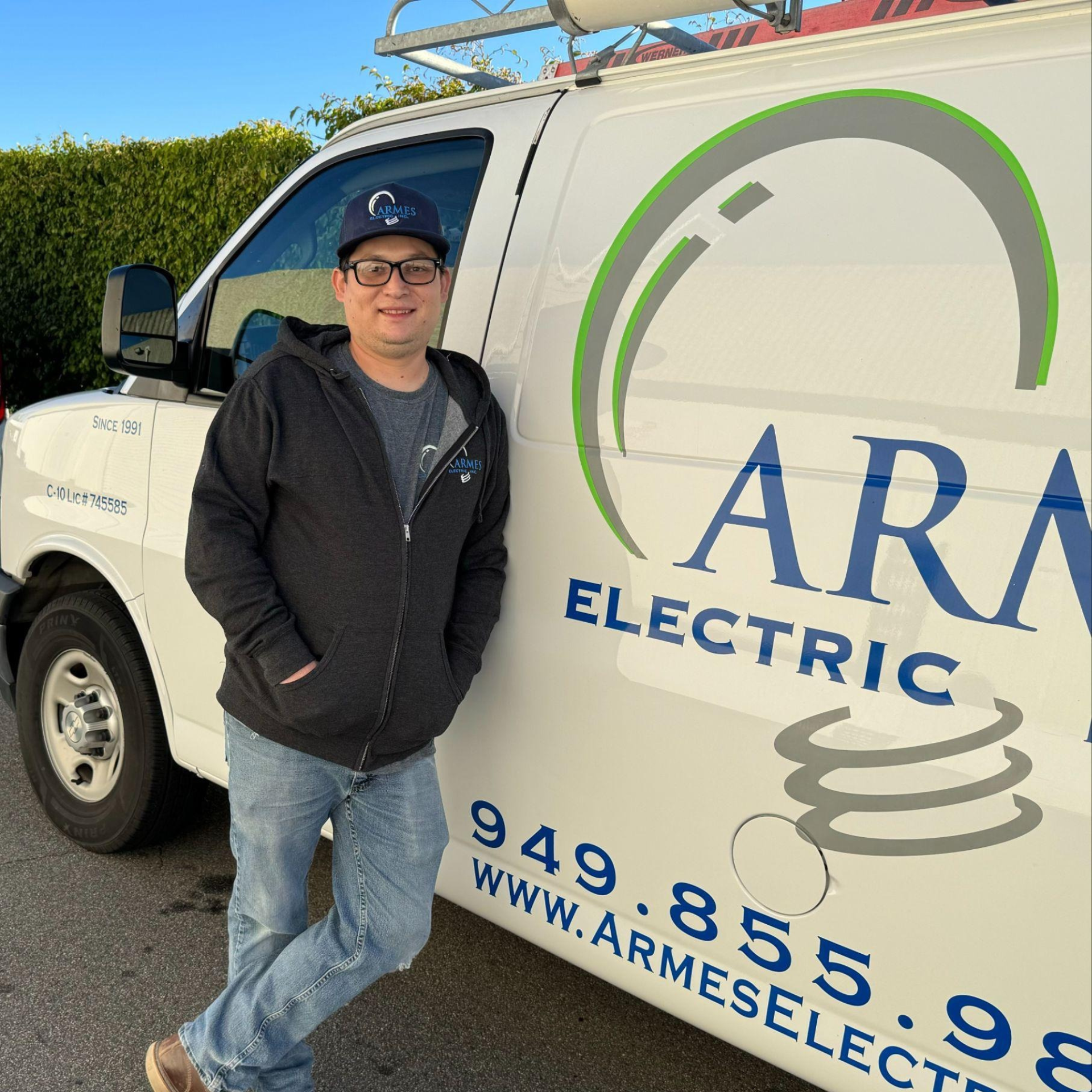 Man standing beside a white ARA Electric service van with company logo and phone number.