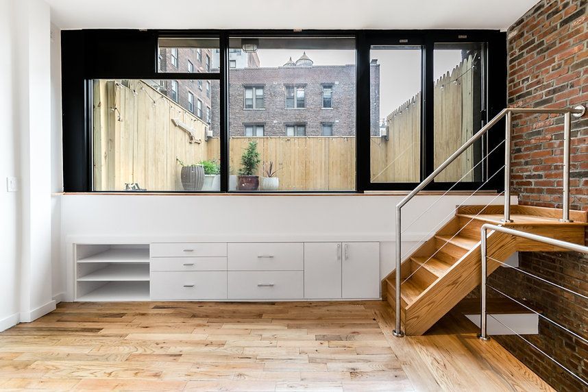 An empty room with a wooden staircase and a large window.