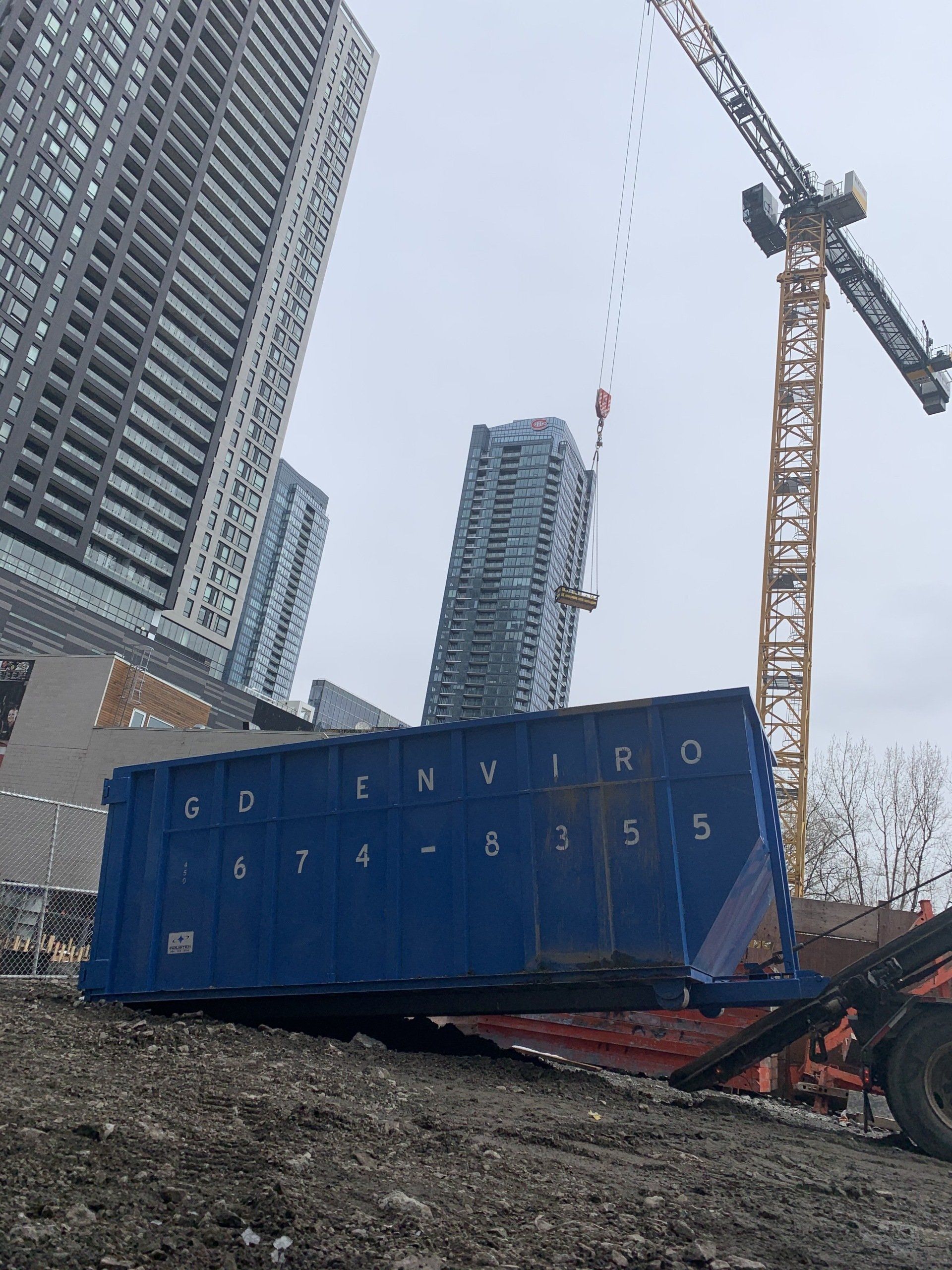 Conteneur maritime bleu sur un chantier de construction avec une grue et de hauts immeubles en arrière-plan
