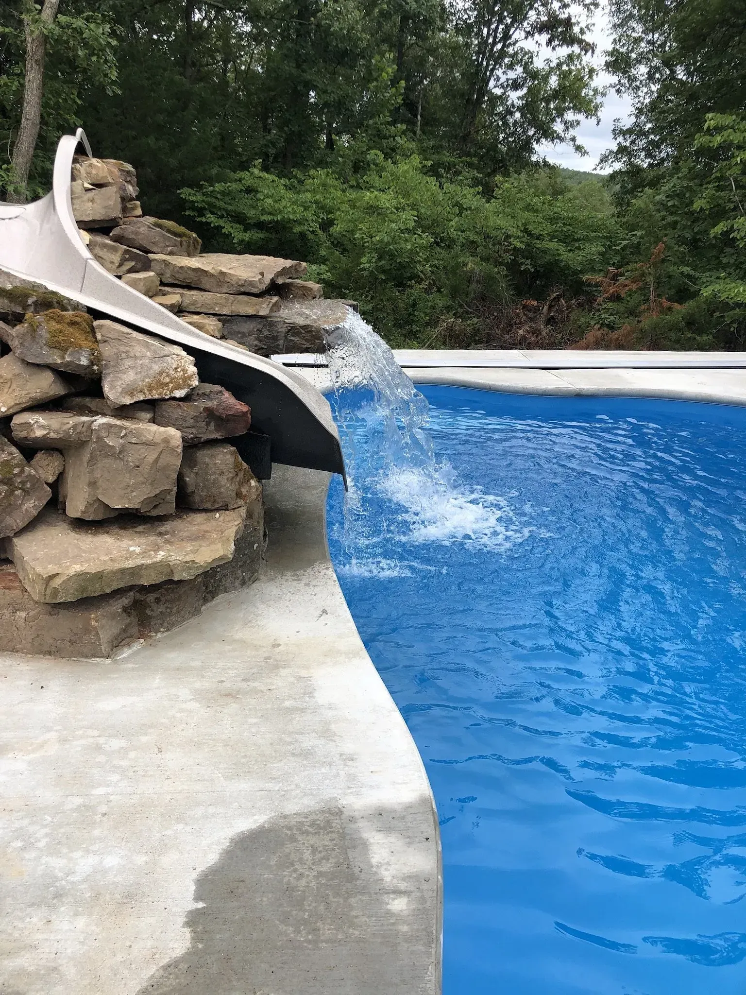 pool with slide on a decorative rock wall