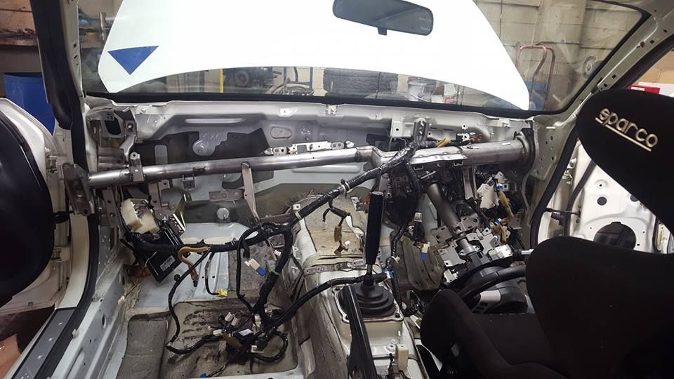 The inside of a race car with the hood open and a sparco seat.