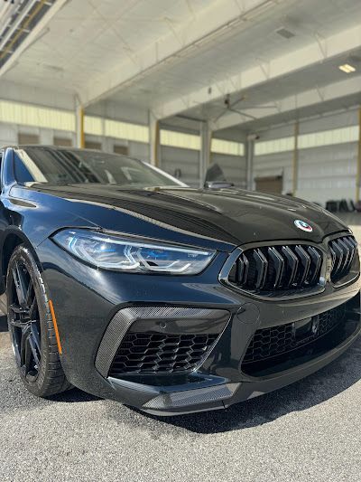 A black bmw m8 is parked in front of a building.
