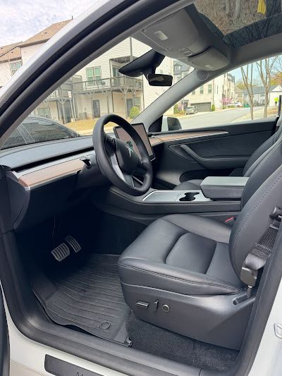 The inside of a white tesla model y with the door open.