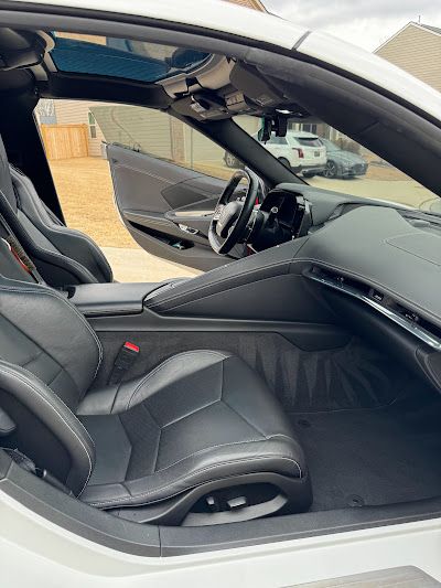 The interior of a white sports car with the door open.