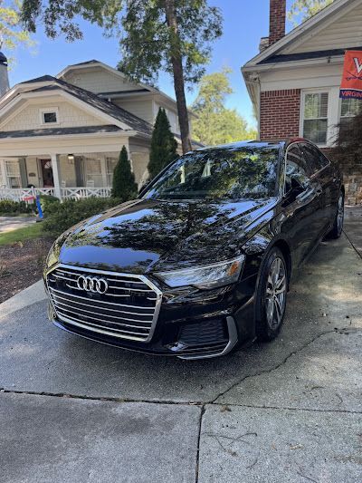 A black audi a6 is parked in front of a house.