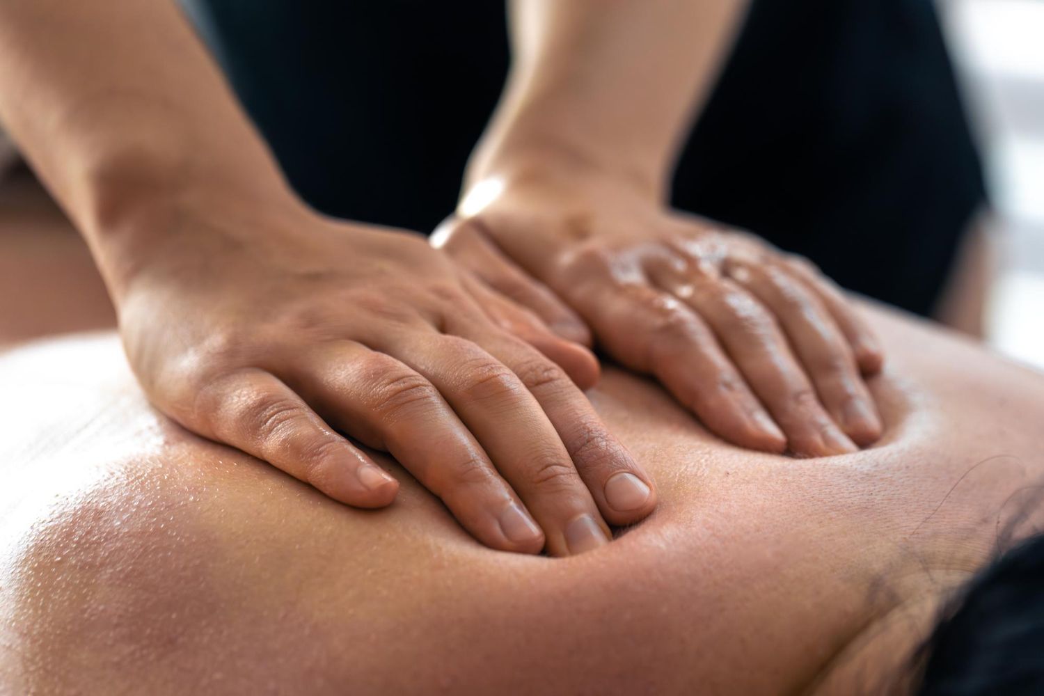 A person receives a therapeutic back massage, with hands applying firm pressure to the skin.