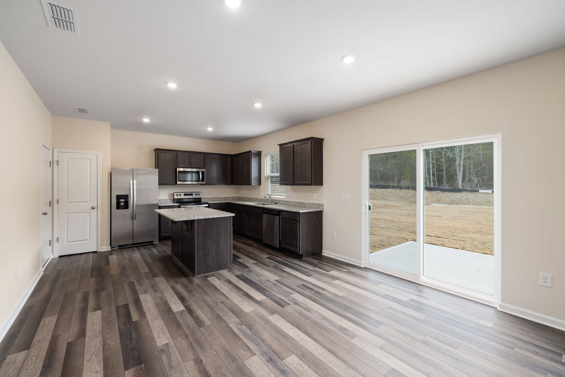 Remodeled open-plan kitchen and living room with dark cabinets and wood-look plank floors