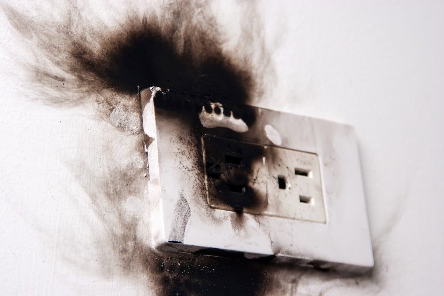 A broken electrical outlet with smoke coming out of it.