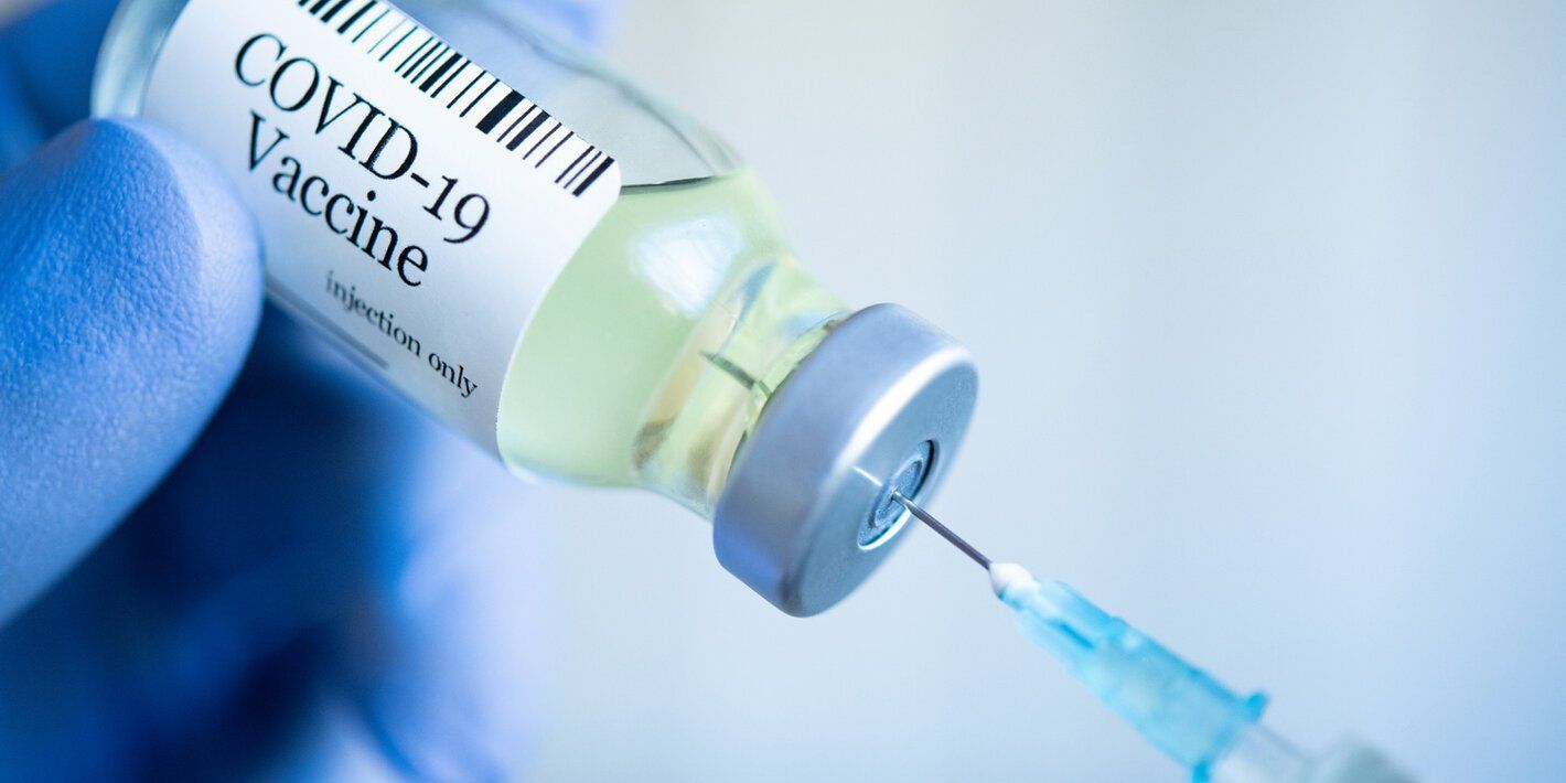 A person is holding a bottle of covid-19 vaccine and a syringe.