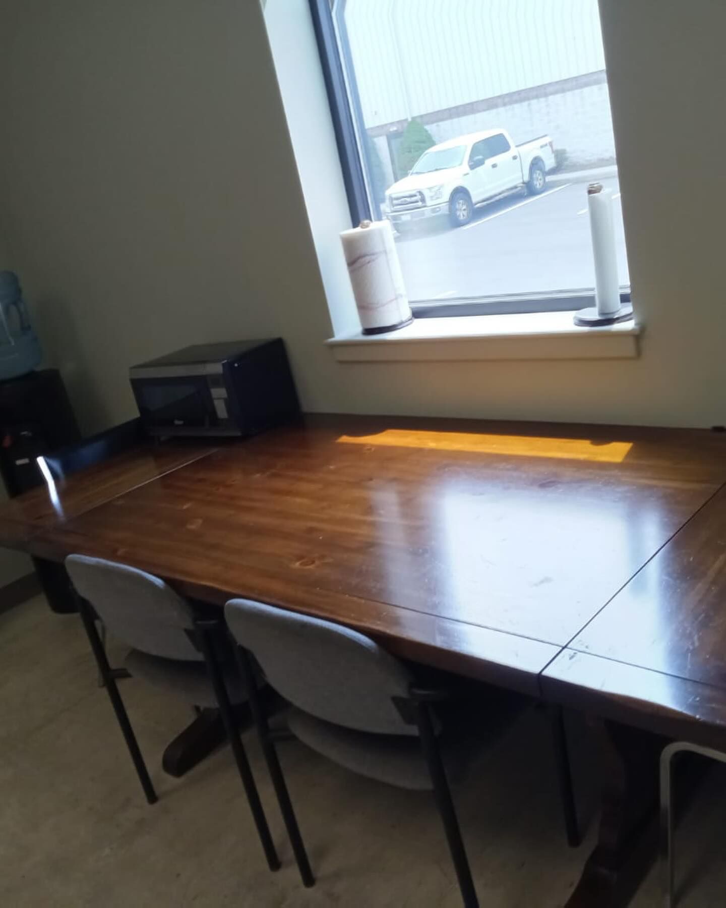 Empty meeting table by a window with sunlight and parked cars outside