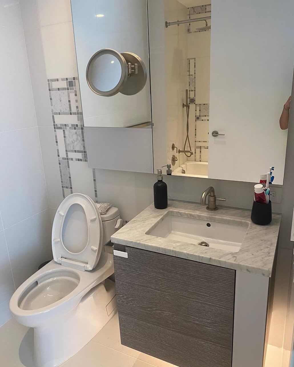 Small bathroom with toilet, sink vanity, mirror cabinet, and white tile walls.