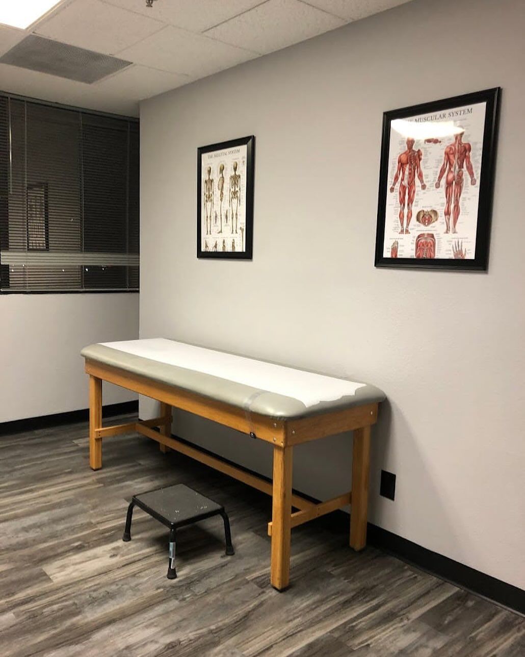Medical exam room with exam table, stool, and anatomical posters on the wall