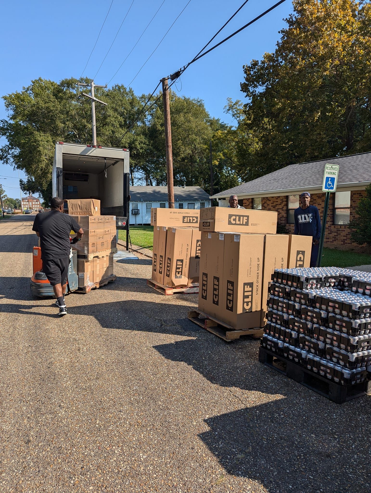 A man is loading boxes into a truck on a gravel road.