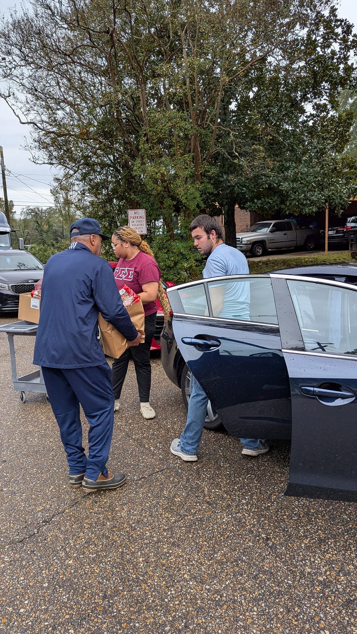 A group of people are loading boxes into a car.