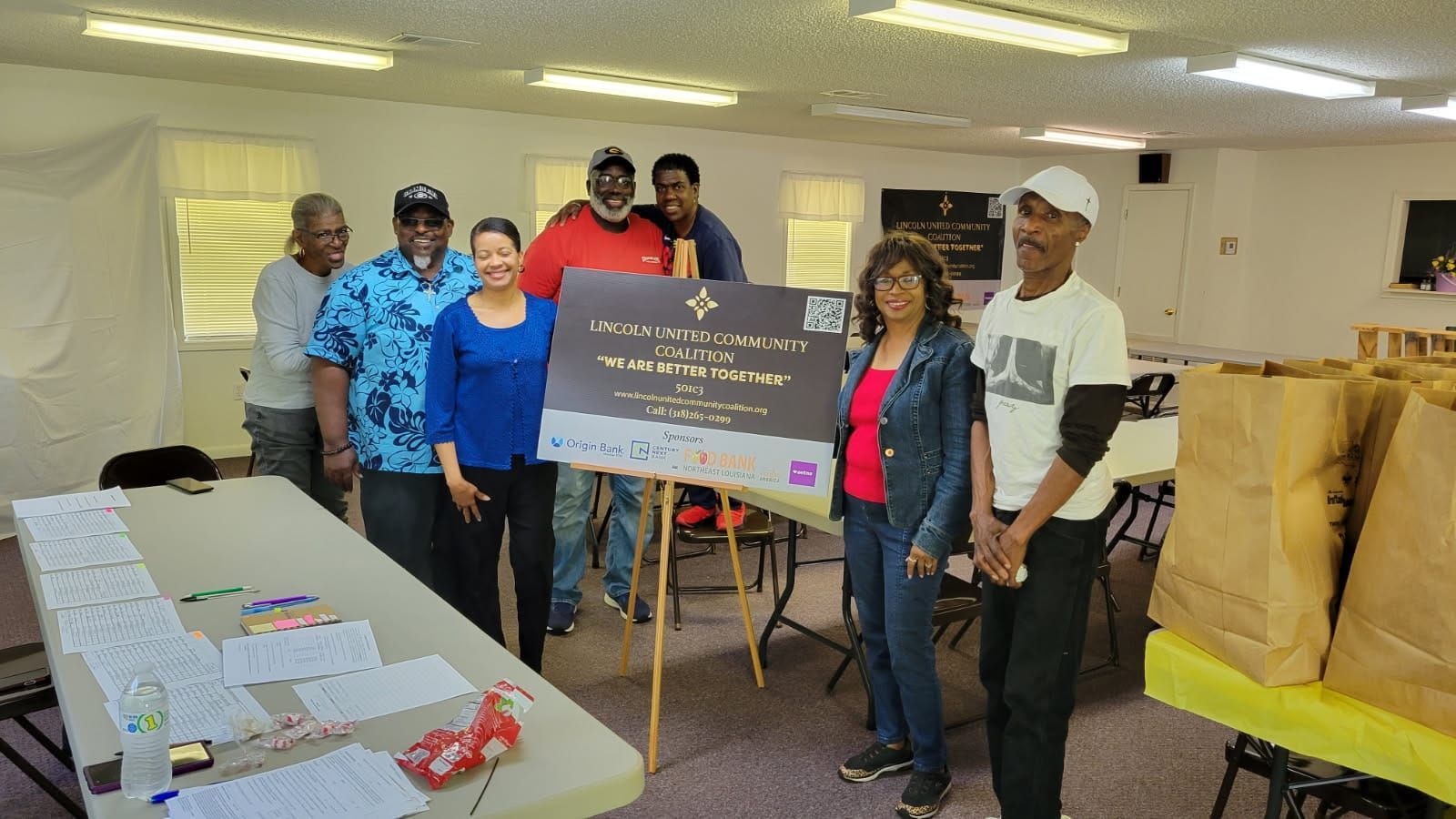 A group of people standing around a table holding a sign.