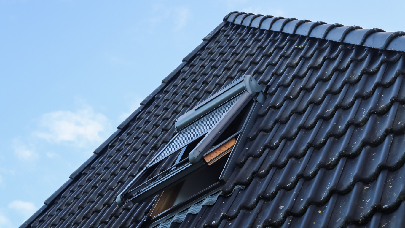 Dormer window on a dark tiled roof against a blue sky