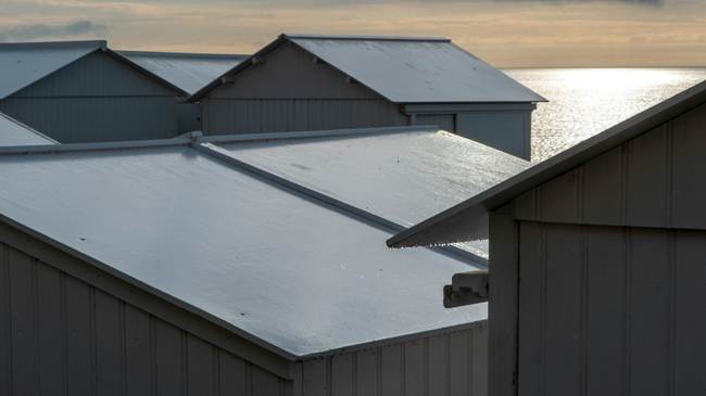 Snow-covered rooftops by the water at sunrise