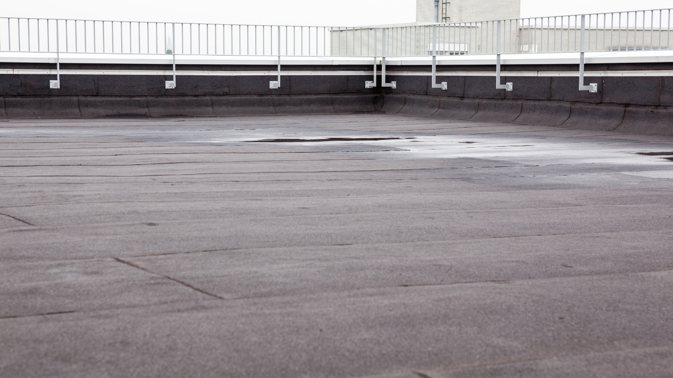 Empty gray rooftop with a railing and a few dark patches on the surface