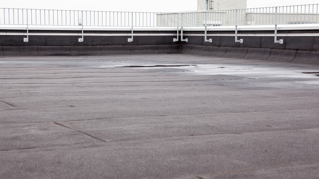 Empty wet rooftop parking lot with a white railing in the background