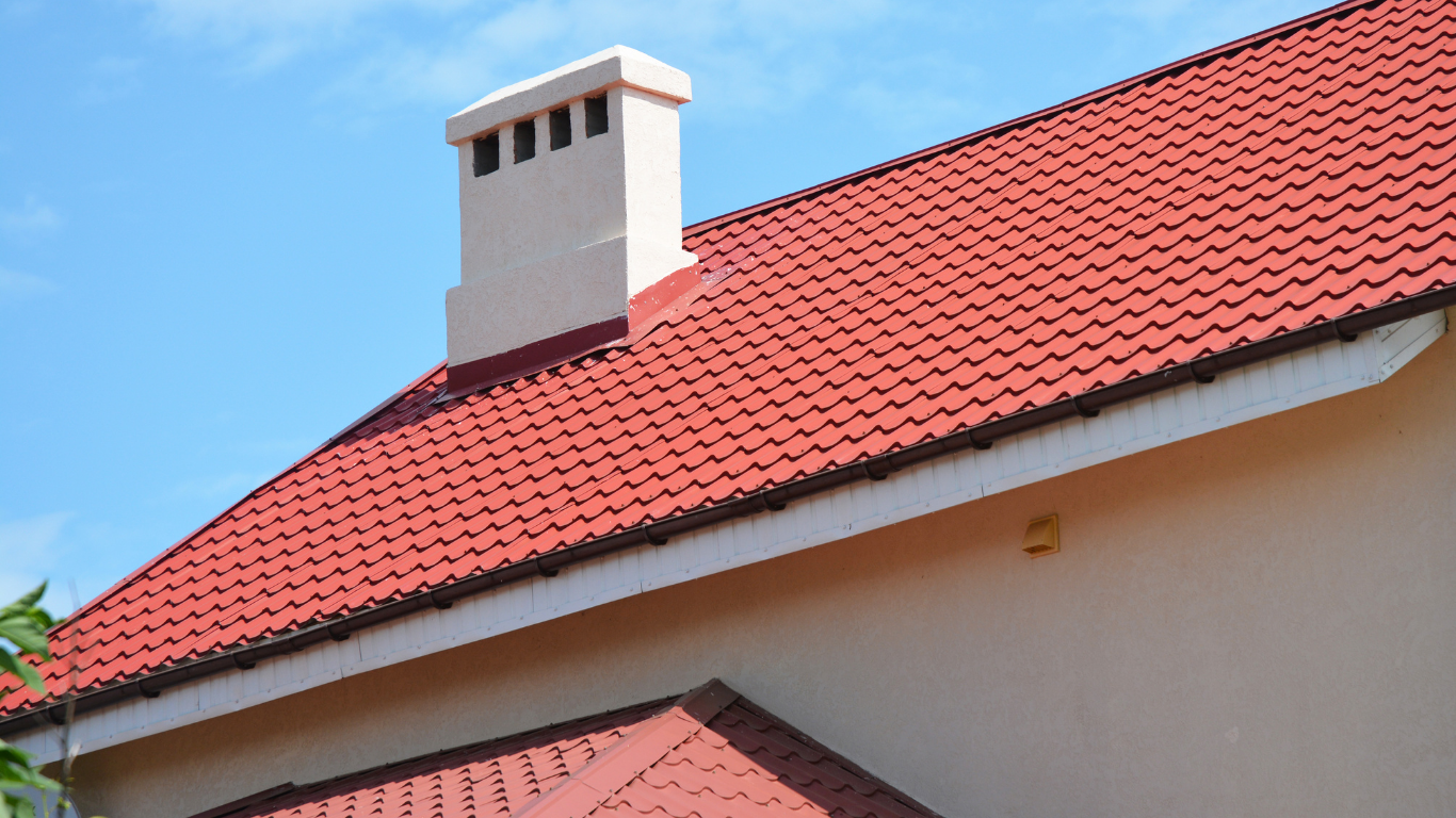 White chimney on a red-tiled roof against a blue sky
