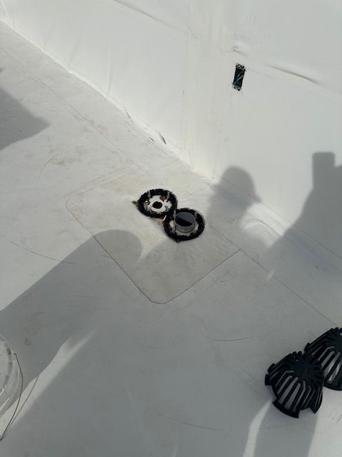 White tiled floor with two small black-and-white round objects and a shadowed person’s legs nearby