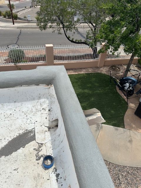View from a balcony of a front yard, street, and parked motorcycle near a fence and tree.
