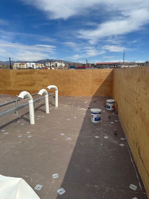 Construction site foundation with white pipes and buckets inside a partially dug trench under a blue sky