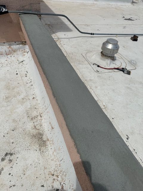 Flat rooftop with a gray waterproofed strip, vent pipe, and loose electrical wires.