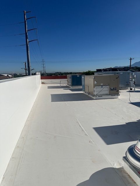 Sunny white rooftop with HVAC units and utility poles under a clear blue sky