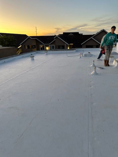 Person standing on a white rooftop at sunset with houses in the background