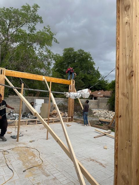 Construction workers framing a building site with wood beams and braces under a cloudy sky