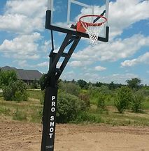 A basketball hoop is sitting in the middle of a field.