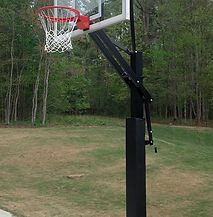 A basketball hoop is sitting in the middle of a grassy field.