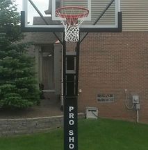 A basketball hoop is sitting in front of a brick house.