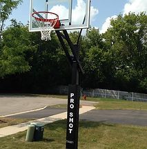 A basketball hoop is sitting in the middle of a park.